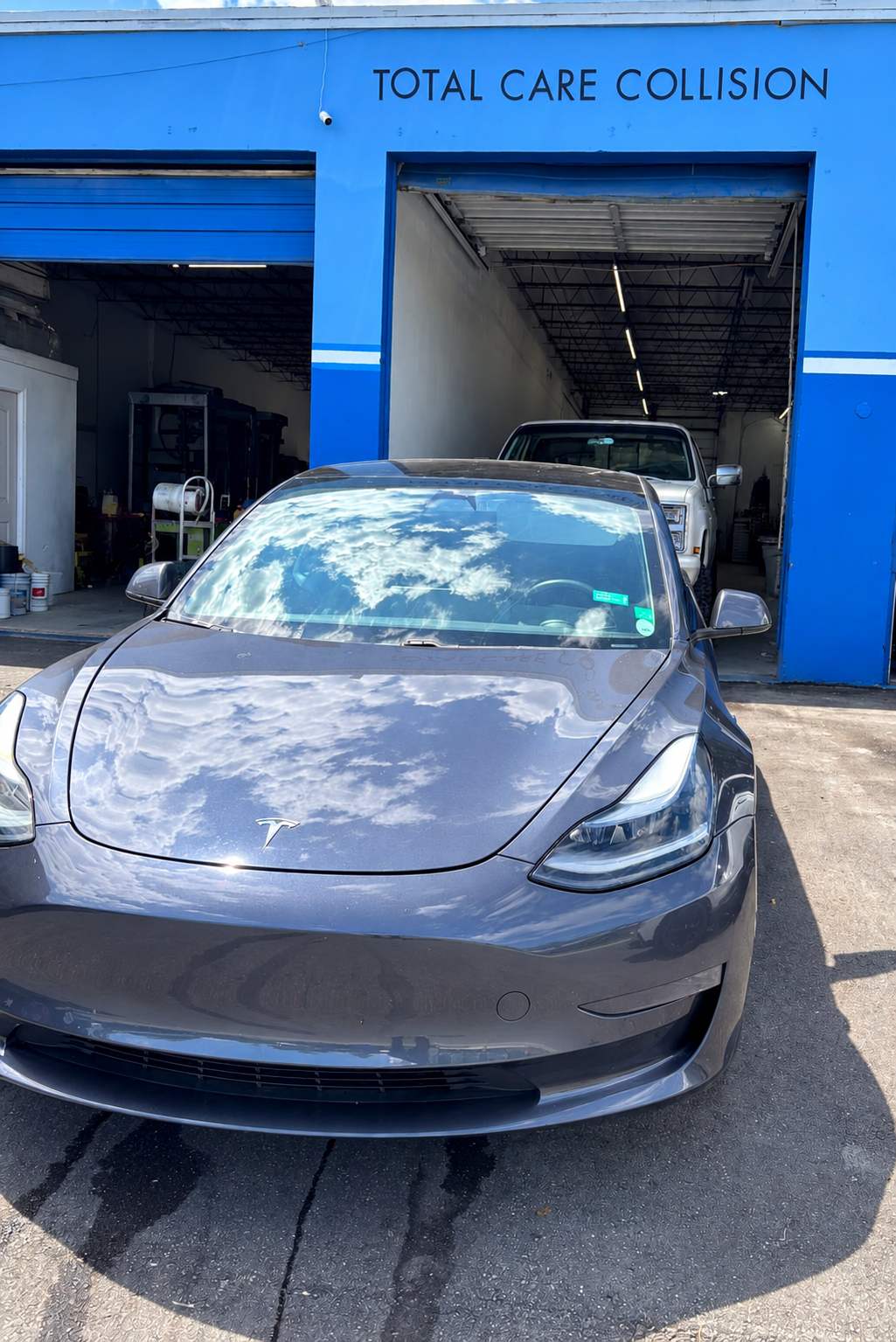Grey Tesla Model 3 in front of the Total Care Collision shop in Pompano Beach FL
