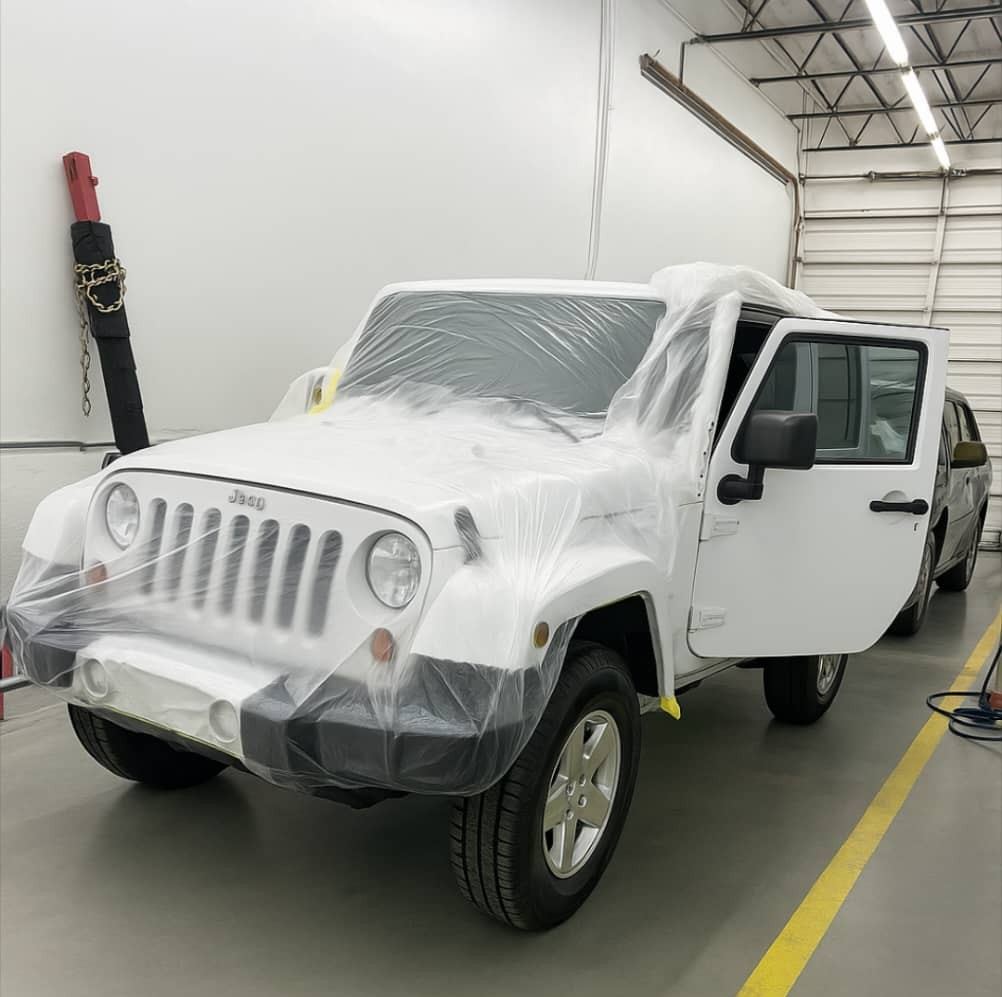 White Jeep Wrangler fully masked in plastic in the paint prep area — Total Care Collision Pompano Beach FL