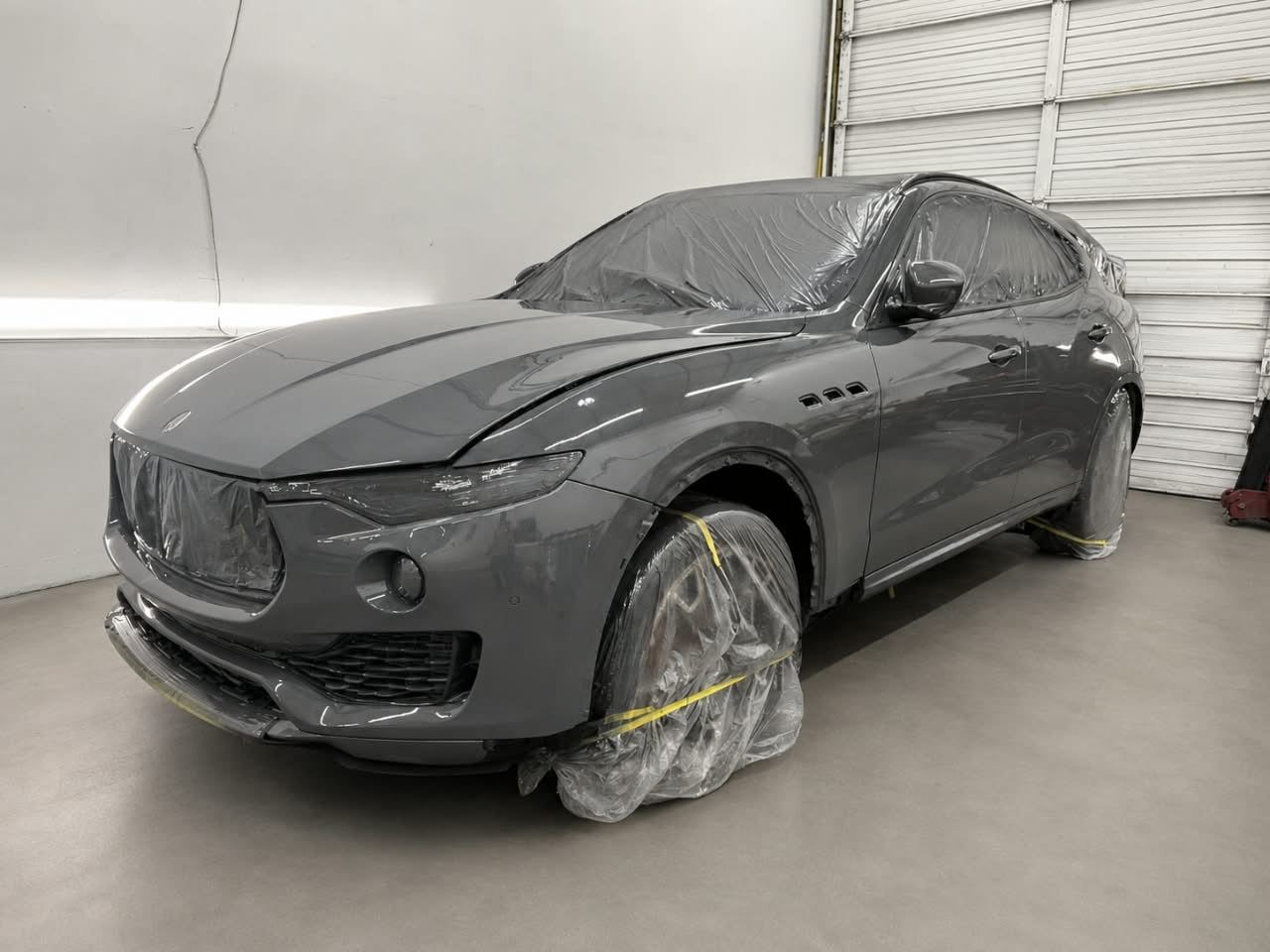 Grey Maserati Levante masked for paint in the spray area — Total Care Collision Pompano Beach FL